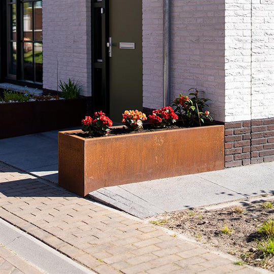 Ein selbstgebauter Blumenkasten aus Cortenstahl. Der rechteckige Kasten hat eine rostbraune Patina und ist mit verschiedenen bunten Blumen bepflanzt.