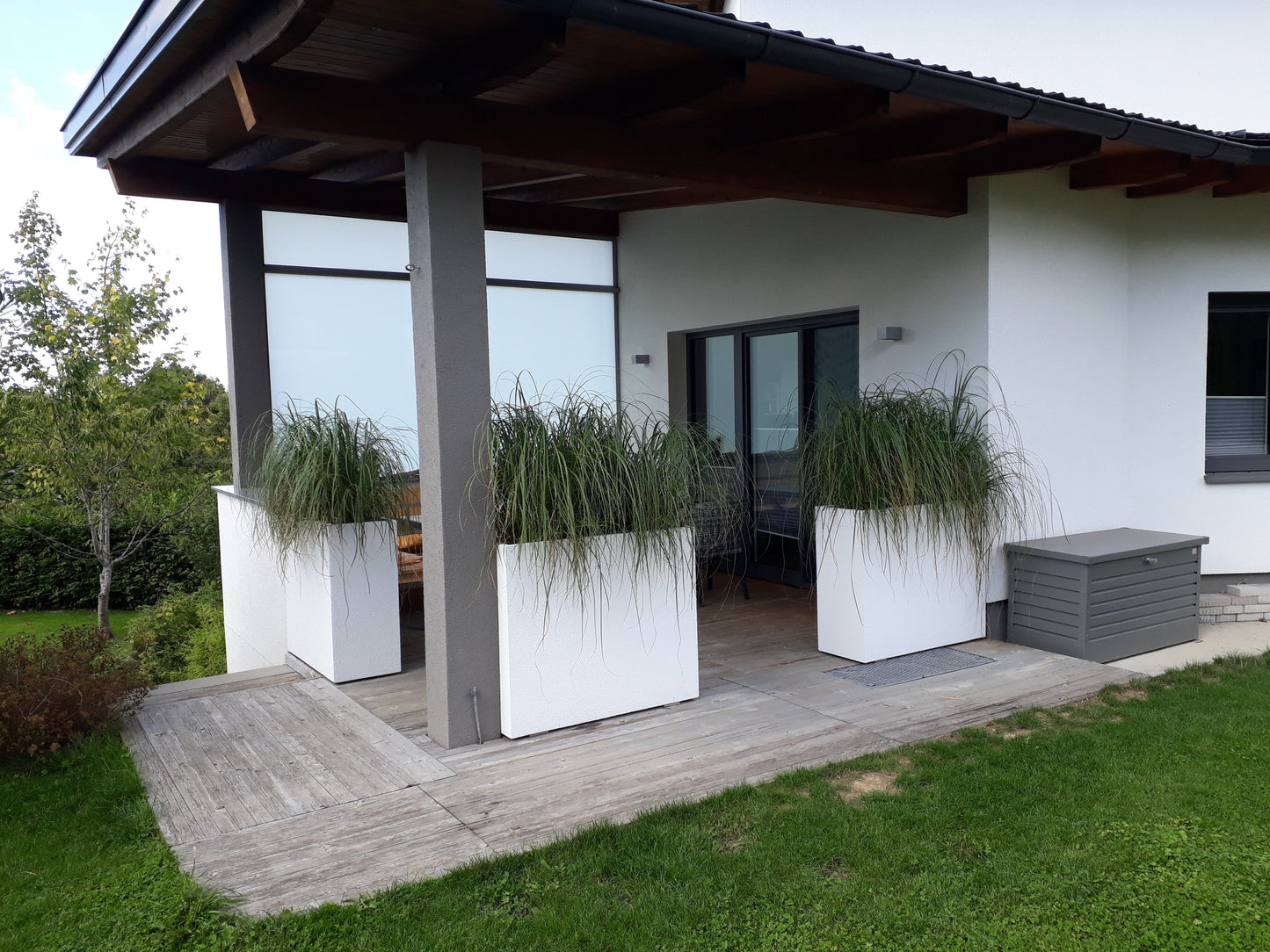 weiße Blumenkästen bepflanzt auf großer Terrasse