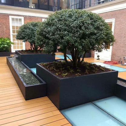 Pflanzkübel aus Aluminium in dunkelgrau. Bepflanzt mit einem Baum.
