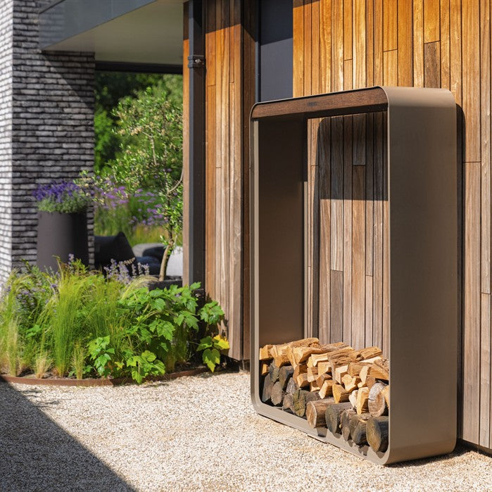 Gerundetes Holzlager CURVA aus Aluminium in Beigegrau mit Bambus-Akzenten mit Brennholz auf der Terrasse