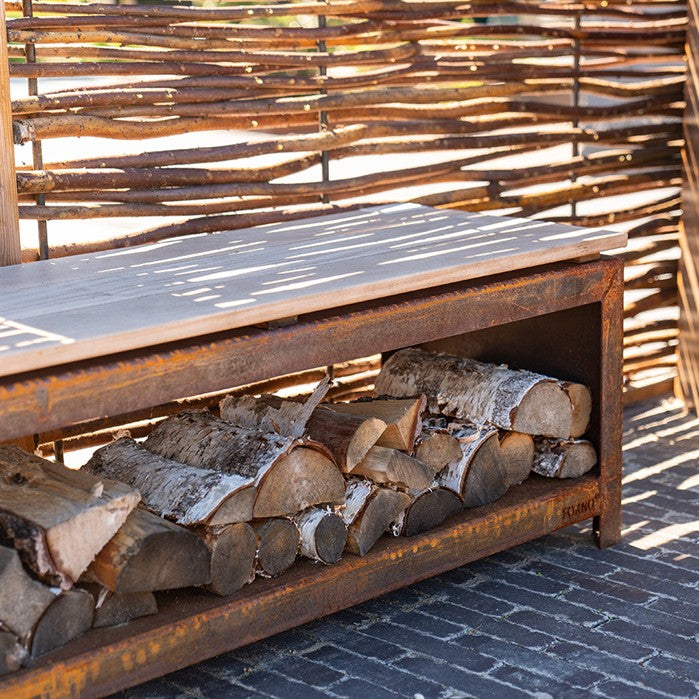 Sitzbank mit Holzlager BANCO aus Cortenstahl mit Brennholz an der Feuerstelle