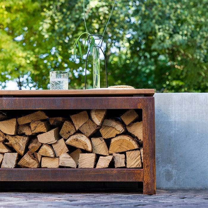 Sitzbank mit Holzlager BANCO aus Cortenstahl mit Brennholz an der Feuerstelle