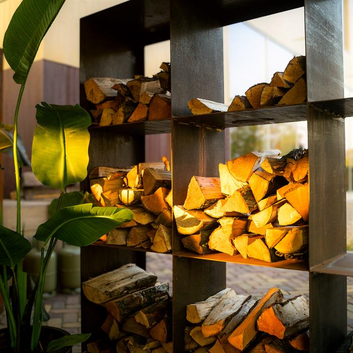 Quadratisches Holzlager CUADRO aus Cortenstahl mit Fächern gefüllt mit Brennholz im Garten