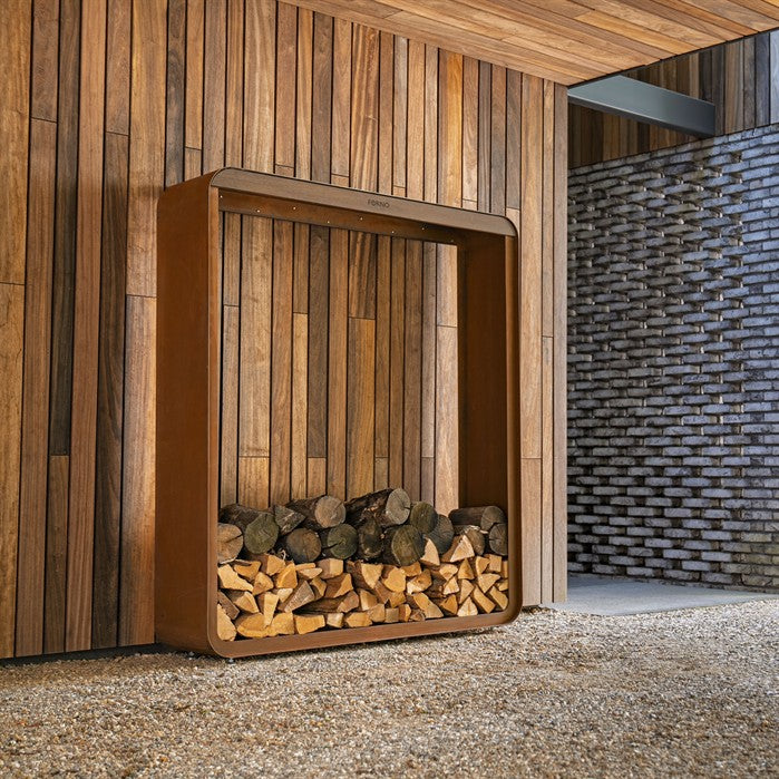 Gerundetes Holzlager CURVA aus Cortenstahl mit Bambus-Akzenten mit Brennholz im Garten