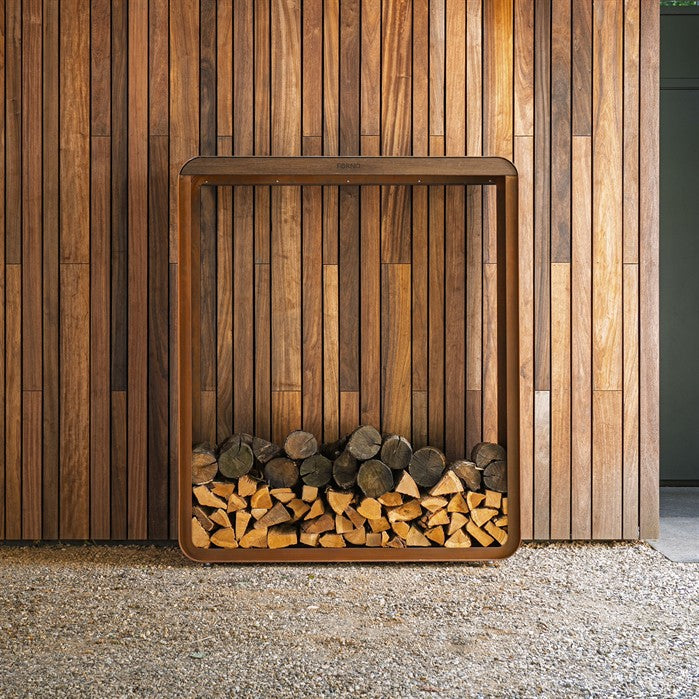 Gerundetes Holzlager CURVA aus Cortenstahl mit Bambus-Akzenten mit Brennholz im Garten