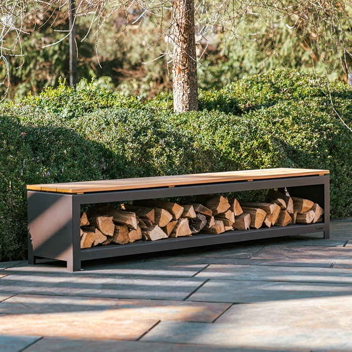 Sitzbank mit Holzlager BANCO aus schwarz beschichtetem Stahl mit Brennholz an der Feuerstelle